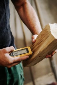 Feuchtemesser wird an einen Brennholzscheit gehalten